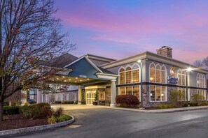 A hotel with a covered entrance, stone facade, and arched windows. - Comfort Inn & Suites East Greenbush - Albany (Castleton-on-Hudson)