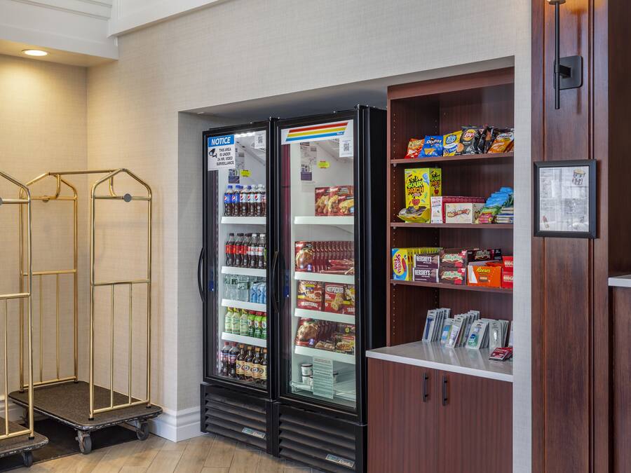 Ein Hotelzimmer mit Minibar, einem mit Getränken und Snacks gefüllten Kühlschrank und einer Holzkabine mit verschiedenen Gegenständen.