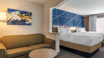 Quarto de hotel com uma cama grande, um sofá, uma mesa redonda e um quadro na parede.