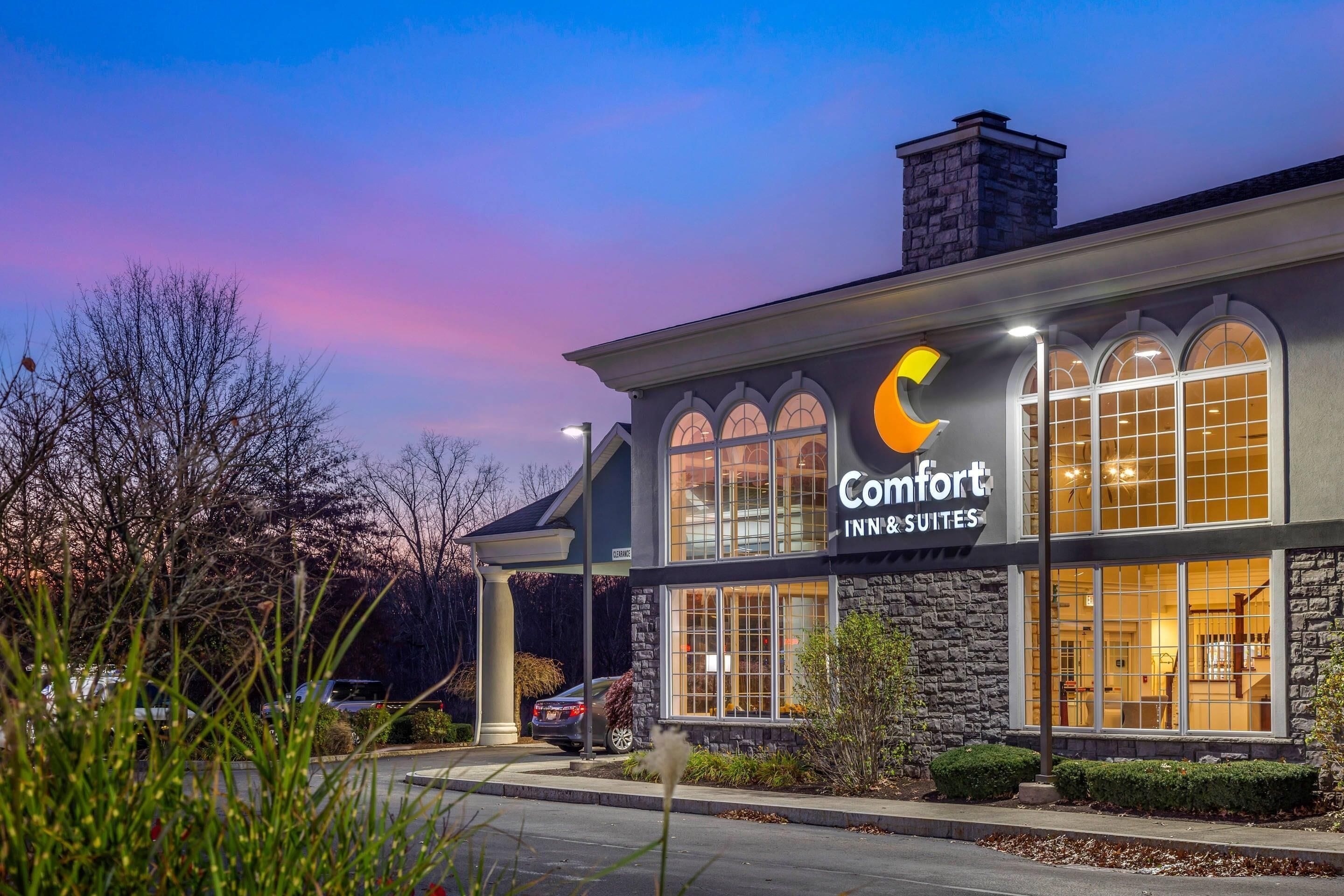 A Comfort Inn & Suites hotel with a stone facade, large arched windows, and a parking lot.