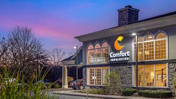 A Comfort Inn & Suites hotel with a stone facade, large arched windows, and a parking lot.