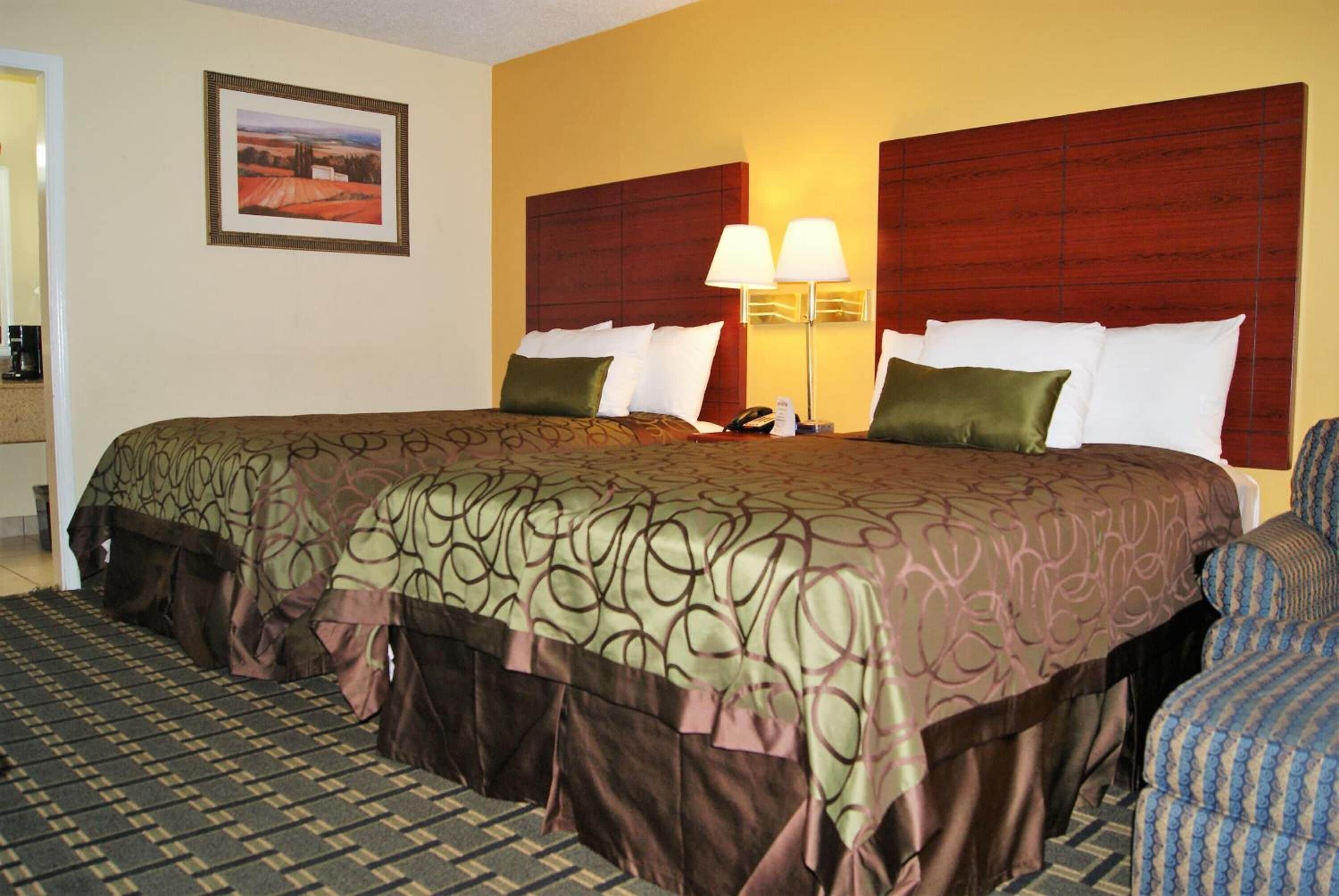 Habitación de hotel con una cama grande, dos lámparas de noche, una mesita de noche y un cuadro en la pared.
