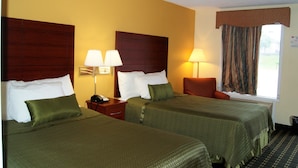 Une chambre d’hôtel avec deux lits, chacun agrémenté de draps verts, d’une tête de lit en bois, d’une table de chevet avec une lampe et d’une fenêtre avec des rideaux.