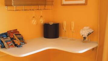 Eine Bar mit einer weißen Arbeitsplatte, einem Metallhocker und einem Bilderrahmen mit einem Champagnerglas.
