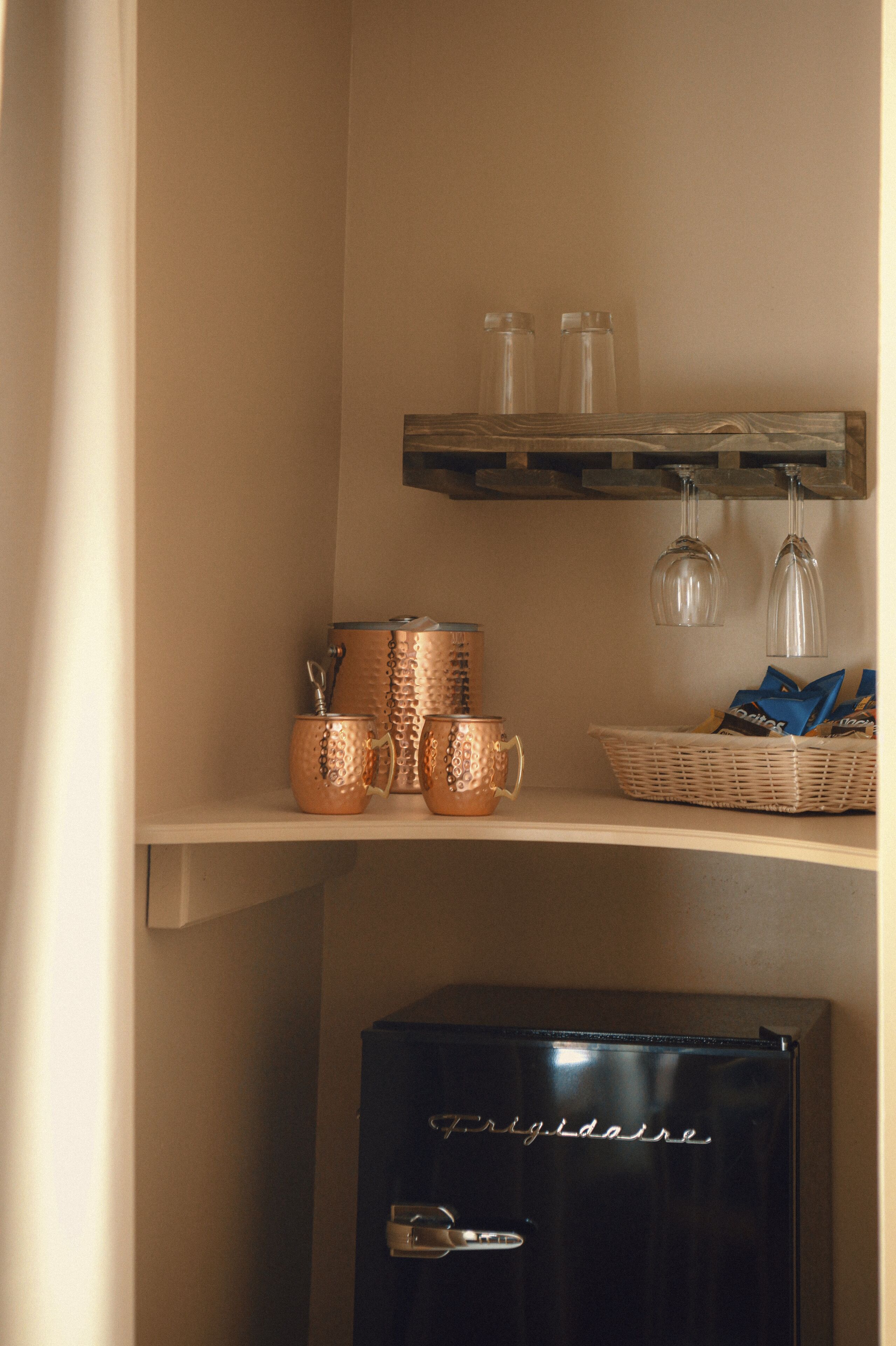 A kitchen area with copper cookware, a basket of snacks, and a black refrigerator.