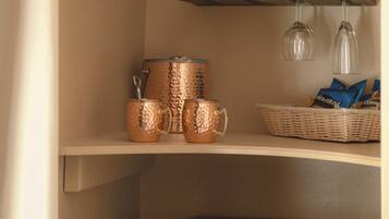 A kitchen area with copper cookware, a basket of snacks, and a black refrigerator.