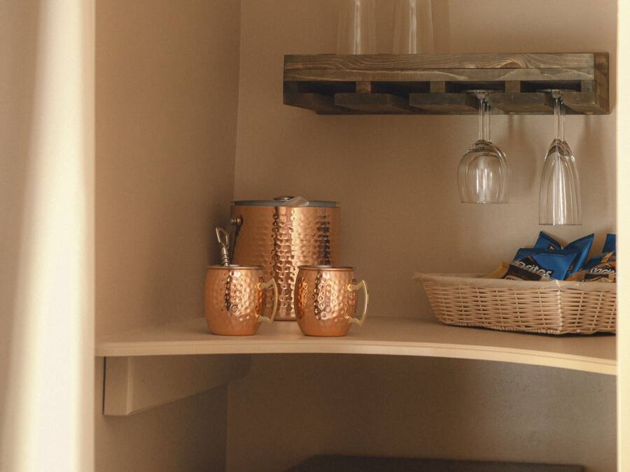 A kitchen area with copper cookware, a basket of snacks, and a black refrigerator.