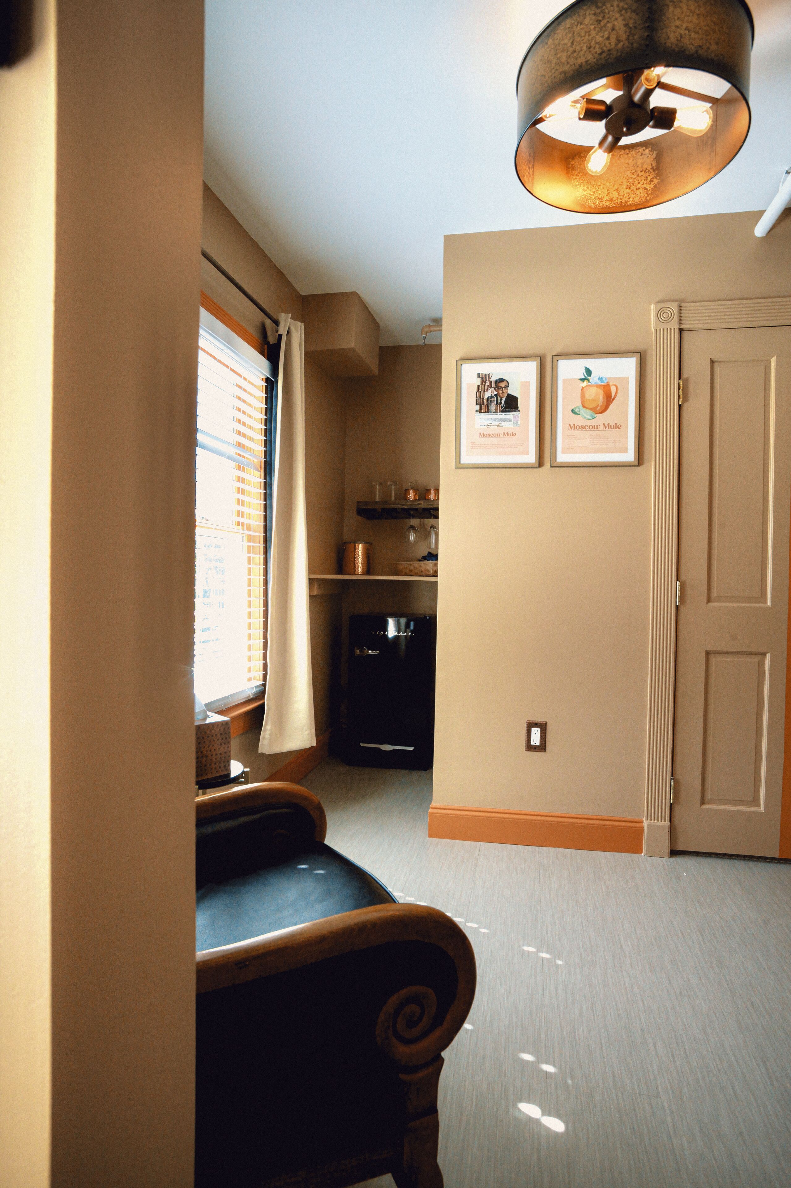 A hallway with a bench, a ceiling light fixture, a door, and two framed pictures on the wall.
