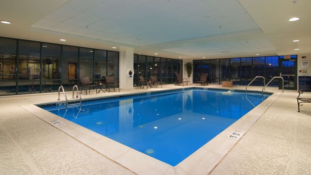 Una piscina interior con agua cristalina, rodeada de paredes de vidrio y un suelo de baldosas.