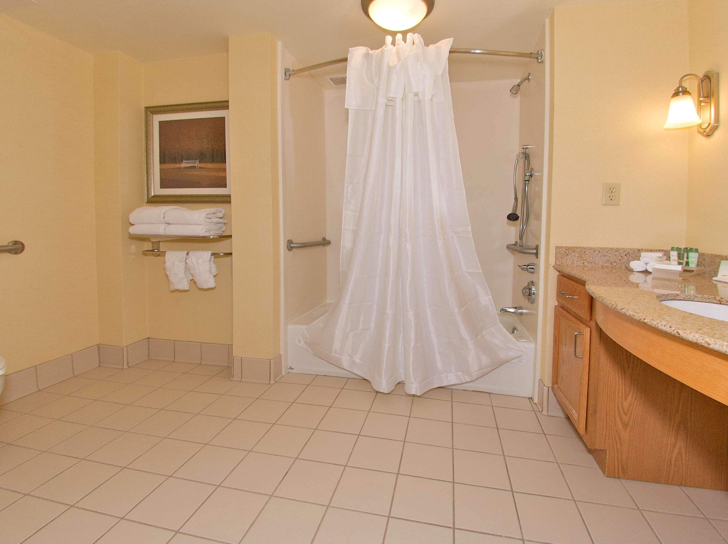 A bathroom with a shower curtain, a sink, a mirror, and a towel rack with towels.