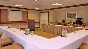 A conference room with a long table, chairs, a podium, and a projector screen.