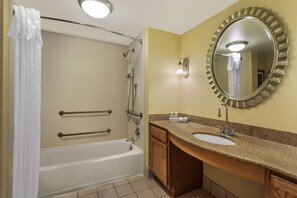 A bathroom with a bathtub, a sink, and a mirror. - Homewood Suites by Hilton Newark-Wilmington South Area (Newark)