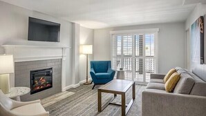 Una sala de estar con chimenea, un sillón azul, un sofá y una mesa de centro.