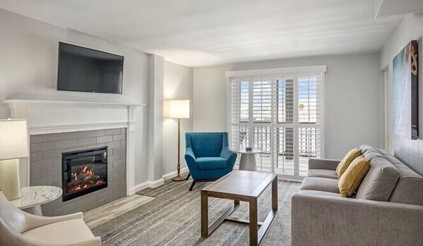 A living room with a fireplace, a blue armchair, a sofa, and a coffee table.