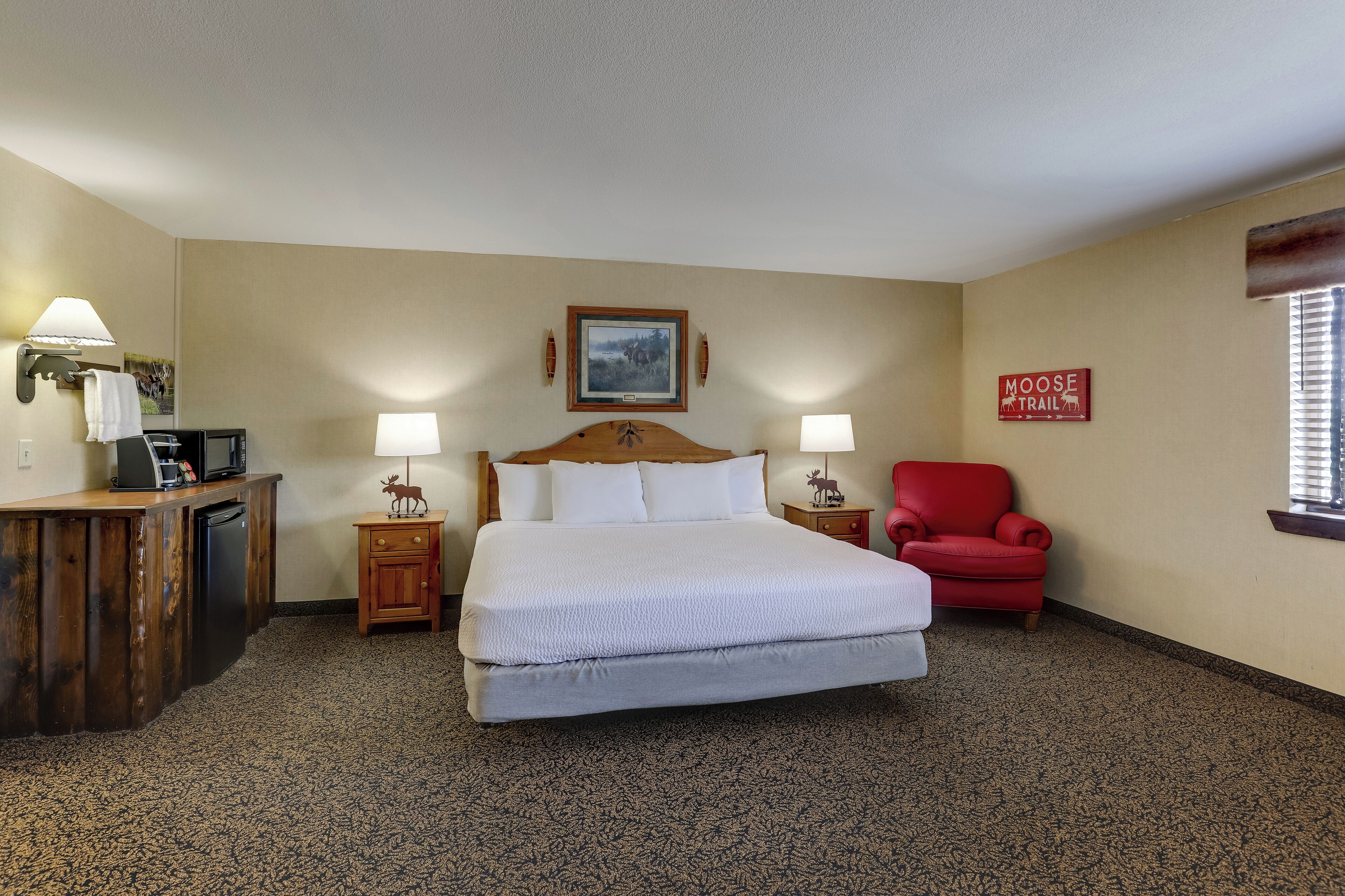 A hotel room with a large bed, a desk with a computer, a chair, and a sign on the wall.