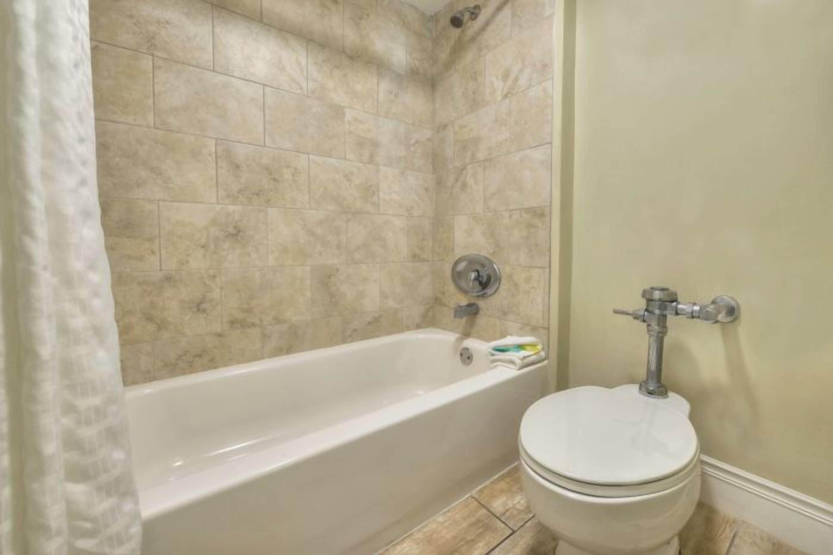 A bathroom with a bathtub, toilet, and tiled walls.