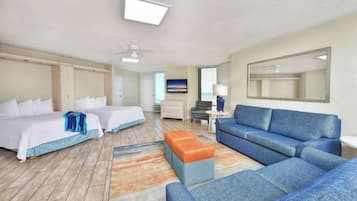 A hotel room with two beds, a sofa, a coffee table, and a desk.