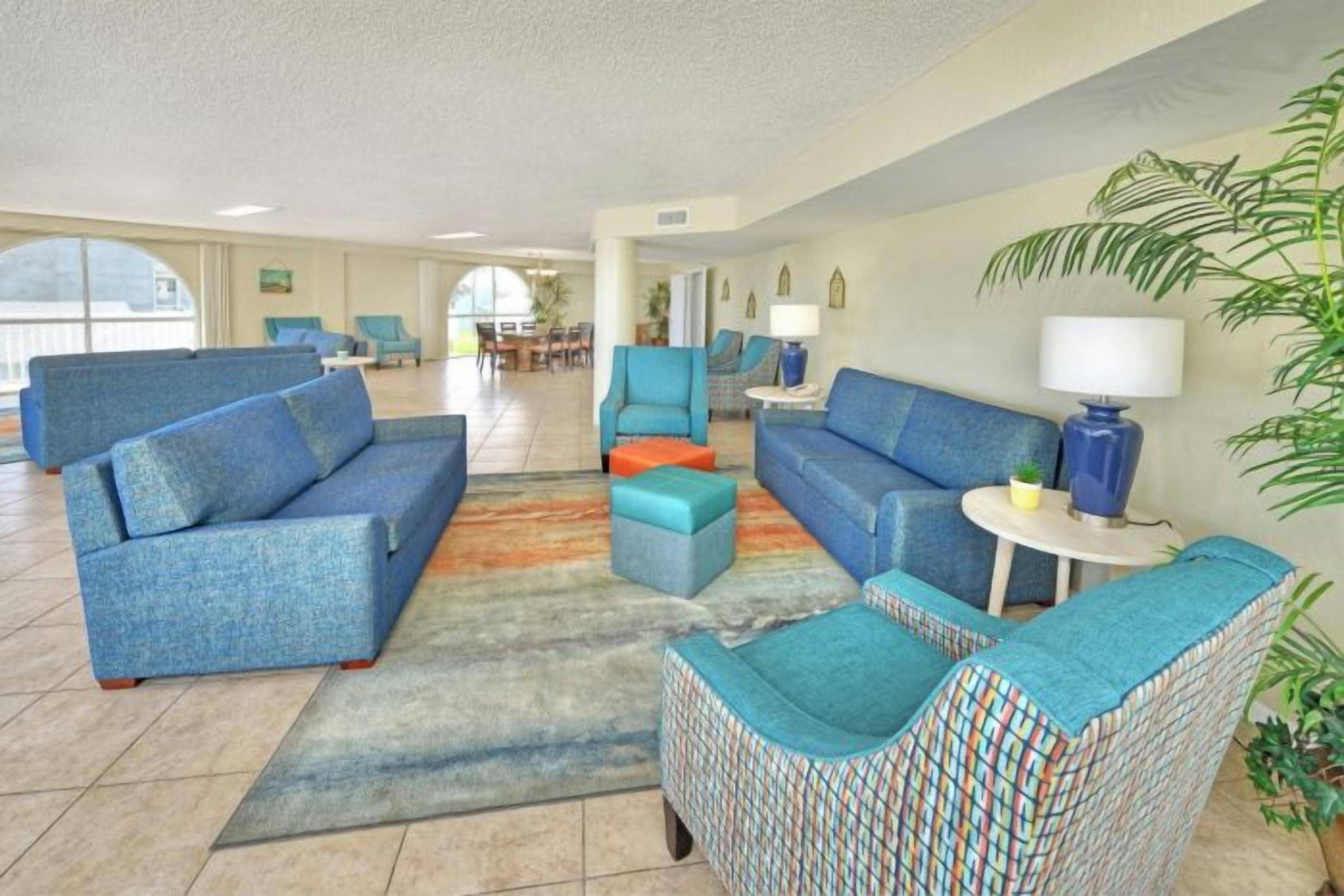 Eine geräumige Lobby mit blauen Sofas, einem gemusterten Sessel und einem kleinen Tisch mit Lampe.