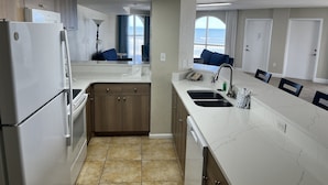 Una cocina moderna con una isla grande, horno empotrado y vistas al océano a través de un ventanal.