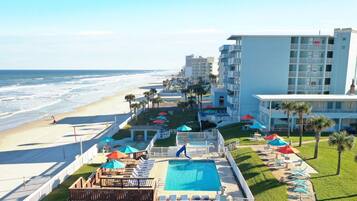 A beachfront hotel with a swimming pool, beach access, and multiple balconies.