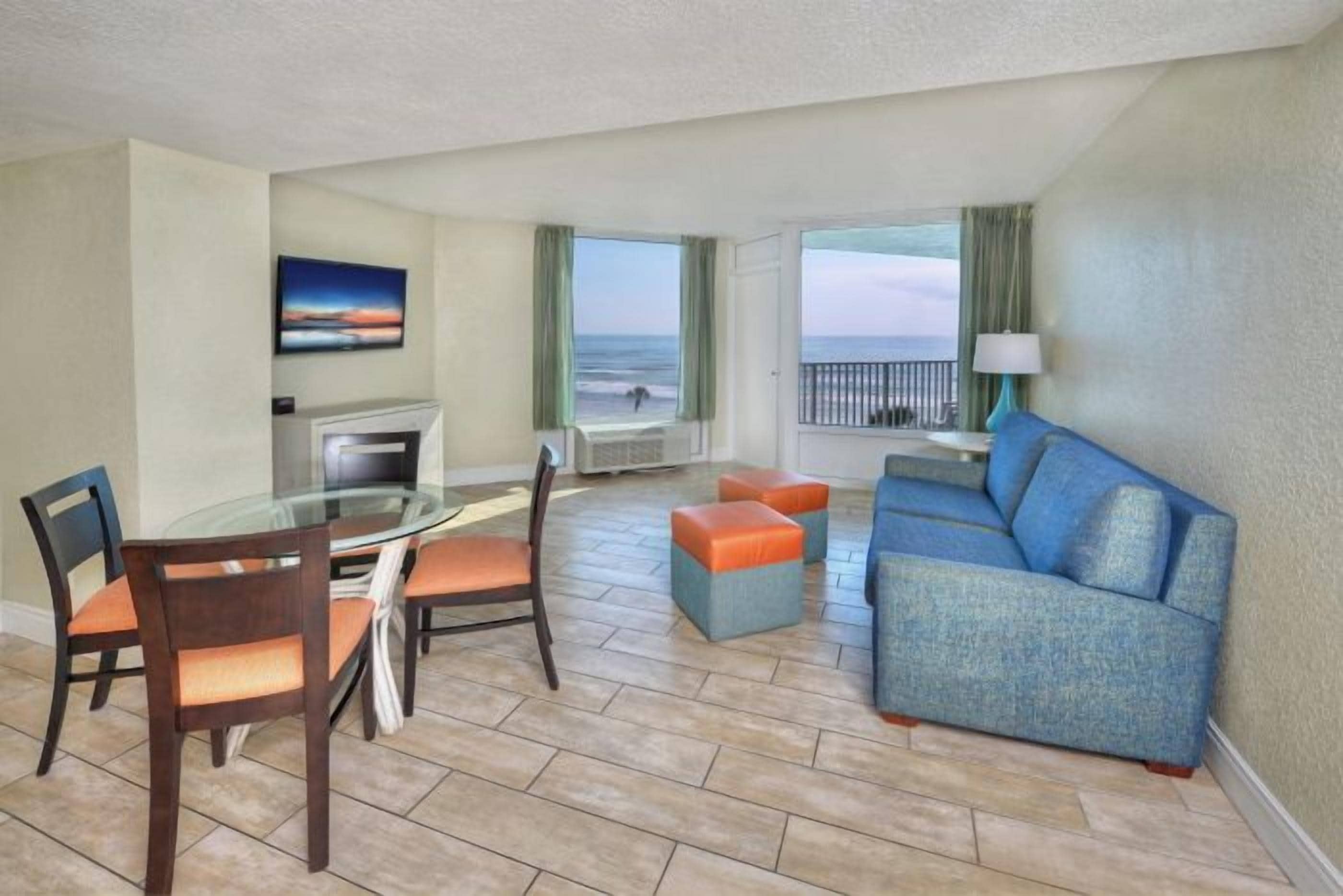 Una habitación de hotel con una mesa de comedor, sillas, un sofá y vista al océano.
