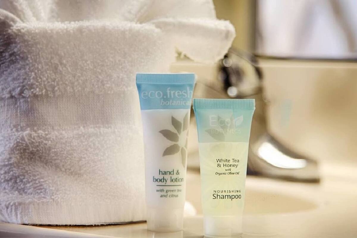 Ein Badezimmer mit einem weißen Handtuch, Hand- und Körperlotion sowie einer Shampooflasche.