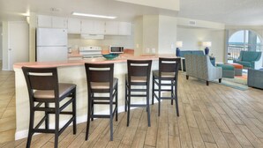 Una cocina moderna con una isla central, taburetes de bar y un área de comedor con vistas.