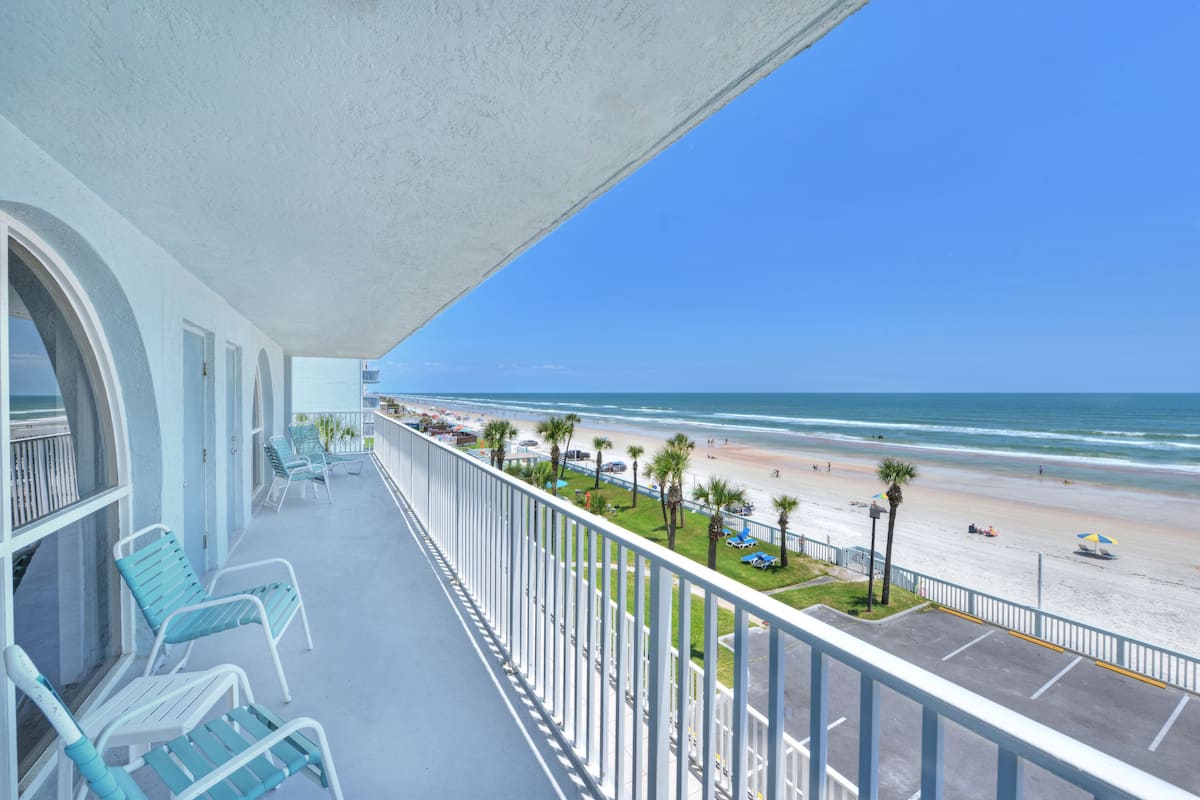 Ein Balkon mit Blick auf den Strand, inklusive Liegestühle und einer Brüstung.