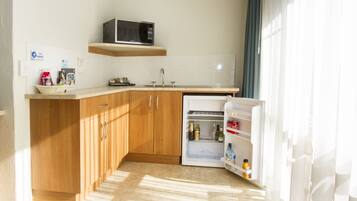 Una cocina funcional con armarios de madera, microondas, refrigerador y pileta.