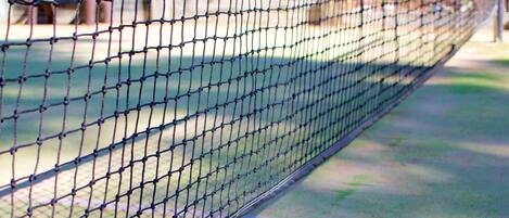 Un court de tennis avec un filet, deux raquettes de tennis et une balle de tennis.
