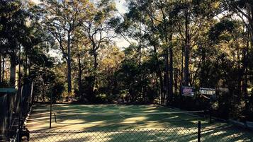 A tennis court surrounded by trees and a fence.
