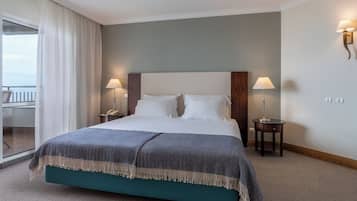 A hotel room with a large bed, two bedside lamps, a telephone, and a view of the balcony.