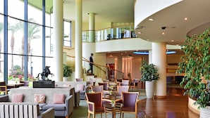A spacious lobby with high ceilings, large windows, and a central seating area with couches and chairs. - Pestana Grand Premium Ocean Resort (Funchal)