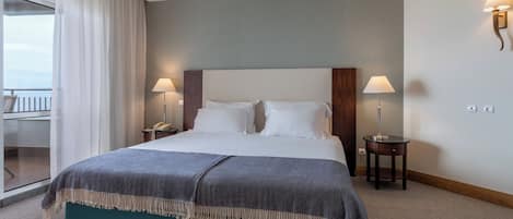 A hotel room with a large bed, two bedside lamps, a telephone, and a view of the balcony.