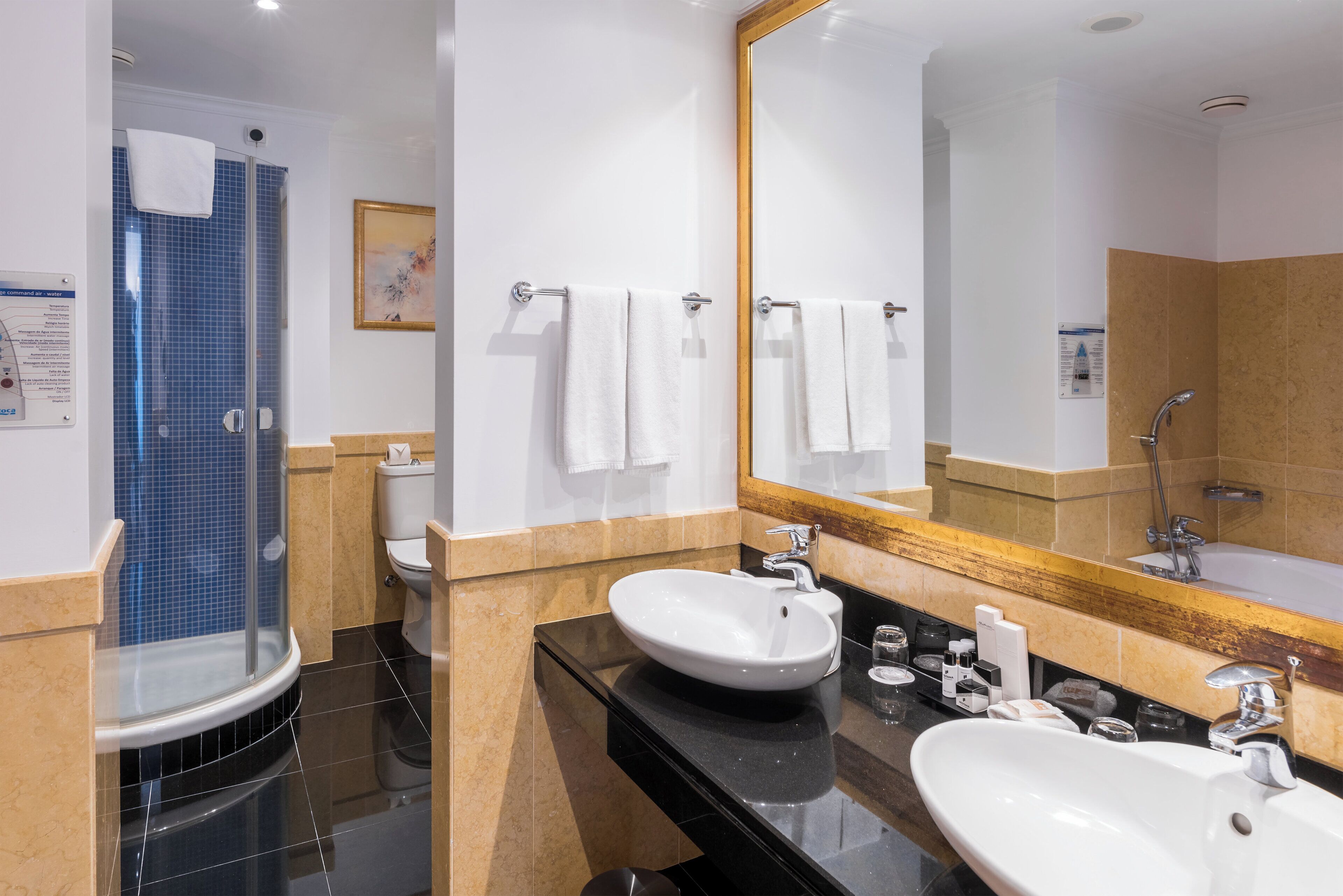 Un baño moderno con ducha envuelta en vidrio, lavamanos blanco, espejo grande y retrete.