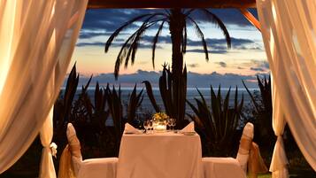 A table set for two with a view of the ocean and palm trees.