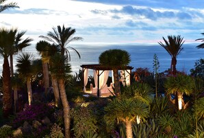 Ein Pavillon mit Blick auf das Meer, umgeben von Palmen und tropischen Pflanzen.
