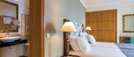 Ein Hotelzimmer mit Bad, einem Bett mit Kissen, einem Nachttisch und einem Beistelltisch.