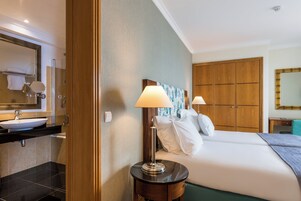 Ein Hotelzimmer mit Bad, einem Bett mit Kissen, einem Nachttisch und einem Beistelltisch.