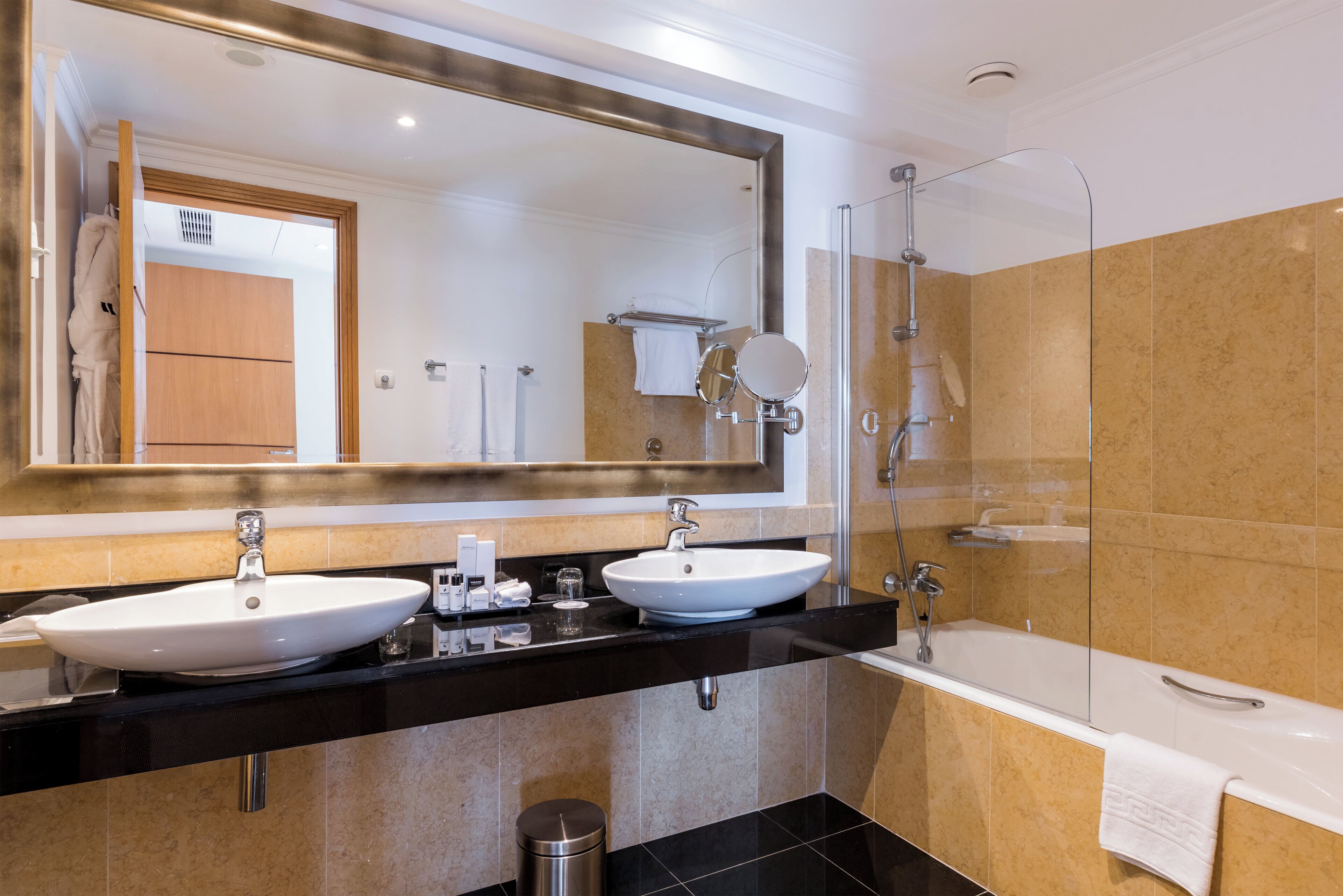 Een moderne badkamer met twee wasbakken, een grote spiegel, een douche en een bad.