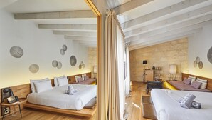 Een moderne hotelkamer met twee bedden, een houten vloer, een stenen muur en een spiegel die de kamer weerspiegelt.