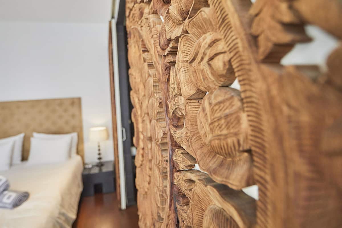 Een slaapkamer met een bed, kussens en een nachtkastje.