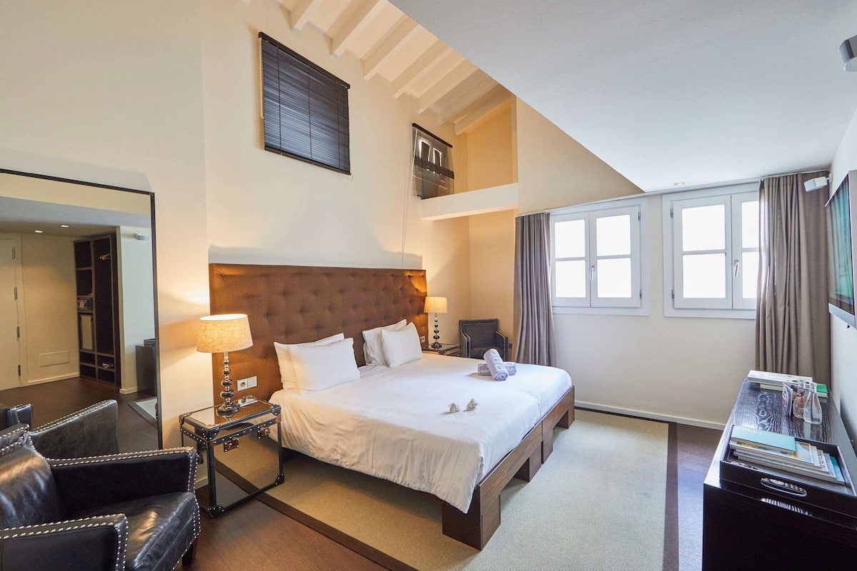 Een hotelkamer met een groot bed, een nachtkastje, een lamp, een stoel en een bureau met een lamp.