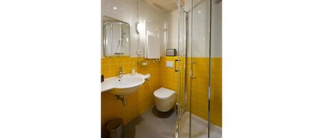 Une salle de bain équipée d’un lavabo, de toilettes et d’une douche à parois de verre.