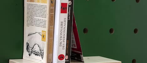 A wooden shelf with books against a green wall.