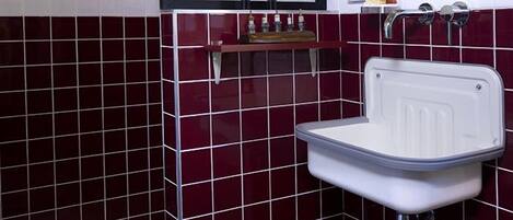 A bathroom with a white sink, a mirror, and a tiled wall.