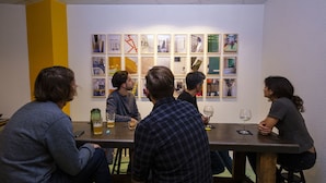 A group of people seated around a table in a room with a white wall and a yellow accent wall. - Artyster Clermont-Ferrand (Clermont-Ferrand)