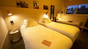 A hotel room with two beds, a small bedside table, a nightstand, and a window with a view of the city at dusk. - Artyster Clermont-Ferrand (Clermont-Ferrand)