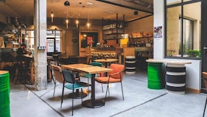 A cafe with tables and chairs, a bar area, and a large window. - Artyster Clermont-Ferrand (Clermont-Ferrand)