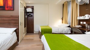 A hotel room with two beds, a desk, a chair, a radiator, a telephone, and a fan. - Marble Arch Inn Hotel (London)